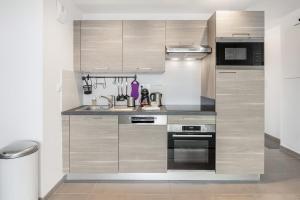 a kitchen with wooden cabinets and a sink at Le Canephora - 800m mer, terrasse, parking, 400m gare in Saint Malo