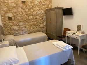 a room with two beds and a stone wall at Corte Sicula in Syracuse
