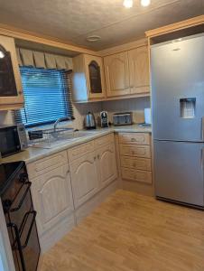 a kitchen with a white refrigerator and wooden cabinets at Aberystwyth holiday village walking distance to beach, town great outside space parking next to property in Aberystwyth