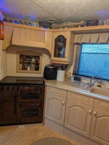 a kitchen with wooden cabinets and a stove and a sink at Aberystwyth holiday village walking distance to beach, town great outside space parking next to property in Aberystwyth +39 photos