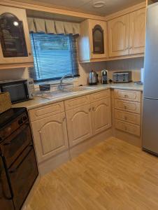 a kitchen with wooden cabinets and a refrigerator at Aberystwyth holiday village walking distance to beach, town great outside space parking next to property in Aberystwyth