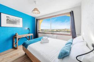 a bedroom with blue walls and a bed with a window at Bellevue, appartement T2, terrasse & parking in Rennes