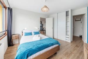 a bedroom with a large bed with a blue blanket at Bellevue, appartement T2, terrasse & parking in Rennes +7 photos