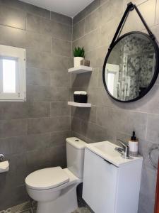 a bathroom with a toilet and a mirror and a sink at Casa Callao 16 con patio in Vigo +9 photos