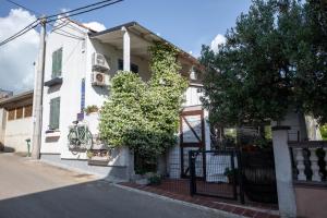 a white house with a gate on a street at Guest house Mediterranea in Pakoštane