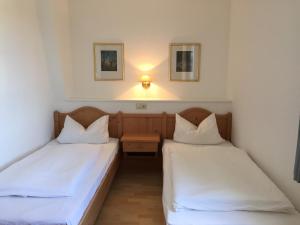 2 Betten in einem kleinen Zimmer mit weißer Bettwäsche in der Unterkunft Ferienwohnung Kemmling in Brilon