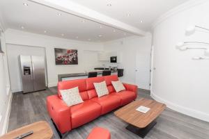 a living room with a red couch and a table at Luxury 1 bedroom top floor apartment in Plymouth