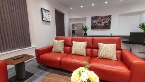 a living room with a red couch and a table at Luxury 1 bedroom top floor apartment in Plymouth