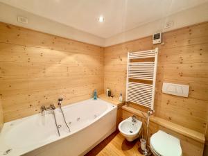 a bathroom with a tub and a toilet in it at Esperienza Unica al Passo Giau - Appartamento con Vista Panoramica in Colle Santa Lucia