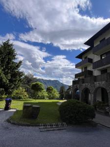 a building next to a park with mountains in the background at Appartamento Levico lake in Levico Terme