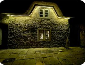 a building with a window with lights on it at Thatch Cottage B&B in Lacock +5 photos