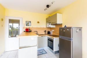 a kitchen with white cabinets and a stainless steel refrigerator at L'Opale - Joli appartement avec jardin et garage in Dinard +2 photos