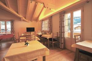 un restaurante con mesas, sillas y ventanas en B&B Panorama en Gstaad