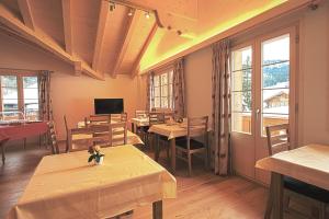 ein Restaurant mit Tischen, Stühlen und Fenstern in der Unterkunft B&B Panorama in Gstaad