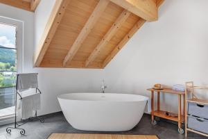 a large white bath tub in a bathroom with a wooden ceiling at Schonzeit Chalet in Bernau im Schwarzwald +28 photos