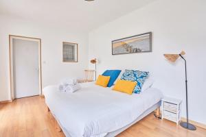 a white bed with colorful pillows on it in a room at Ker Lys - Grande maison avec 4 chambres et jardin in Dinard