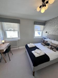 a bedroom with a bed and a desk and two windows at Edenhurst By Pureserviced in Plymouth