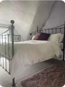 ein Schlafzimmer mit einem Bett mit weißen Laken und Kissen in der Unterkunft Thatch Cottage B&B in Lacock