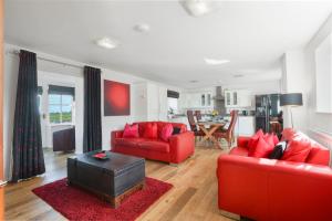 a living room with two red couches and a kitchen at Stable Cottage - North East Escapes in Bamburgh