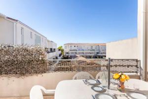 a white table and chairs on a balcony at LE BLEU CAMARGUE - T3 EN DUPLEX CLASSÉ 3 ETOILES - CLIM - ARRIVÉE AUTONOME - Piscine privative à la résidence - Parking Gratuit - Wifi FIBRE - Animaux acceptés - Idéale Famille couple télétravail in Le Grau-du-Roi