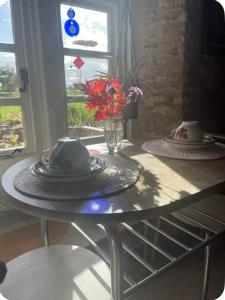 einen Tisch mit Platten und eine Vase Blumen darauf in der Unterkunft Thatch Cottage B&B in Lacock