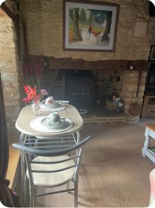 einen Tisch und Stühle in einem Zimmer mit Kamin in der Unterkunft Thatch Cottage B&B in Lacock + 5 Fotos