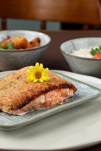 a piece of fish on a plate with a flower on it at Pousada Vila Caminito in Brotas