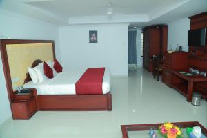 a bedroom with a bed and a desk and a television at hotel savera park in Trichūr