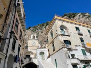 a building with a clock tower in front of a mountain at Starhost - Il Ricordo del Capitano in Atrani