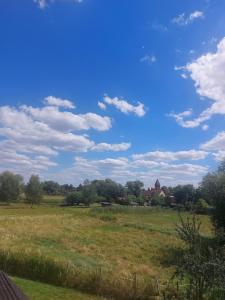 a field with a blue sky and clouds at Charmante Monteurwohnung Ferienwohnung bei Berlin, Tesla in Spreenhagen +9 photos