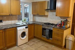a kitchen with wooden cabinets and a washing machine at 2 bed-Sleeps 4-Private Patio-Pets-Near Heathrow in Hounslow
