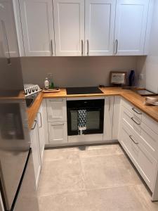 una cocina con armarios blancos y horno negro en Les Flobarts - grande maison de famille en centre ville à 50m de la baie, en Saint-Valery-sur-Somme