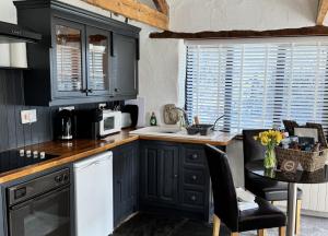 a kitchen with black cabinets and a table with a microwave at Nuthatch by Together Travel - Luxury Cornish Countryside Retreat in Bodmin