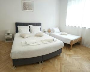 two beds in a bedroom with white walls and wooden floors at Apartman Noel Knin in Knin