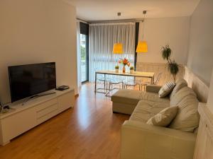 Una sala de estar con un sofá y un televisor de pantalla plana. en La Llum de Sitges, en Sitges