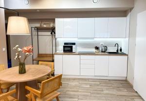 a kitchen with white cabinets and a table with a vase of flowers at Easy Stay Studio #self check-in in Warsaw