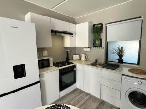 Una cocina con gabinetes blancos y lavadora y secadora. en The Patio, 31 Millennial Arch, en Langebaan 21 fotos más