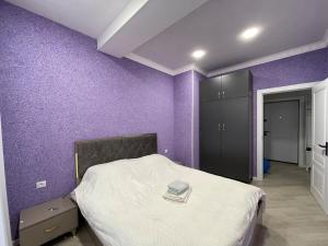 a bedroom with purple walls and a bed in it at Avant Daireleri in Baku