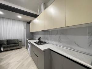 a kitchen with white cabinets and a stove top oven at Avant Daireleri in Baku