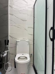 a white toilet in a bathroom with marble walls at Avant Daireleri in Baku +9 photos