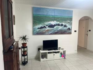 a living room with a tv and a painting on the wall at CASA BARBARA in Ventimiglia