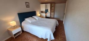 a bedroom with a white bed with a blue headboard at Le gîte de battreau in Massognes