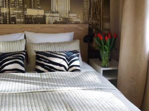 1 dormitorio con 1 cama y un jarrón de tulipanes rojos en Studio Plac Bankowy, en Varsovia