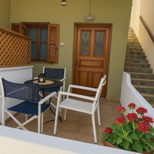 a patio with two chairs and a table and a door at Nicolas Beach in Palaiochora