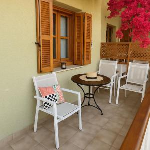 a patio with white chairs and a table and a table at Nicolas Beach in Palaiochora