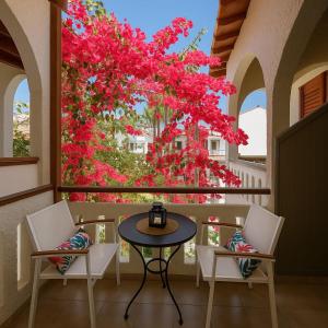 a table and chairs on a balcony with pink flowers at Nicolas Beach in Palaiochora