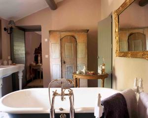 a bathroom with a bath tub and a mirror at Villa Syrah, La Bastide de Marie, Villa avec services in Ménerbes