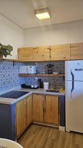 a kitchen with wooden cabinets and a white refrigerator at Loft Santorini no centro com Café da manhã in Alto Paraíso de Goiás
