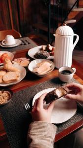a person holding a piece of food on a table with plates of food at Villa montebello Pousada Tanoeiro in Monte Belo +7 photos