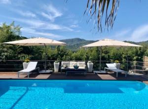 a swimming pool with two umbrellas and chairs next to at La Villetta - cozy house with parking, wifi, wall box and air conditioning in Rapallo